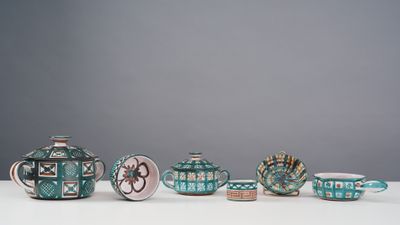 five teapots and two cups sitting on a table