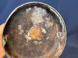 a person holding a metal bowl with a brown substance on it