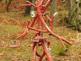 a red sculpture of a man made out of sticks in the woods