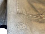 the back of a man ' s beige jacket with a red and blue trim