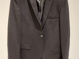 gray suit jacket hanging on a hanger on a white wall