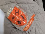 grey quilted jacket with orange and black logo on it