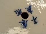a white plate with blue writing on it with a hole in the middle
