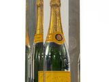 deux bouteilles de champagne dans une boîte transparente posée sur une surface blanche