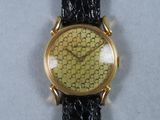 une image représentant une montre en or avec un bracelet noir