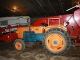 a red and orange tractor parked in a garage