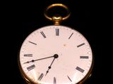 a gold pocket watch with roman numerals on the face