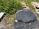 a black stone bench sitting in the middle of a grassy area