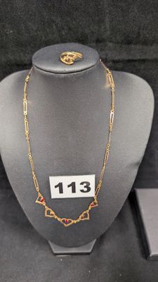 collier à chaîne en or orné de pierres rouges, exposé dans une vitrine