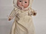 a baby doll that is wearing a white dress and bonnet