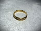 a close up of a gold wedding ring on a white surface