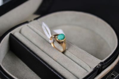 a ring in a case with a green stone in it