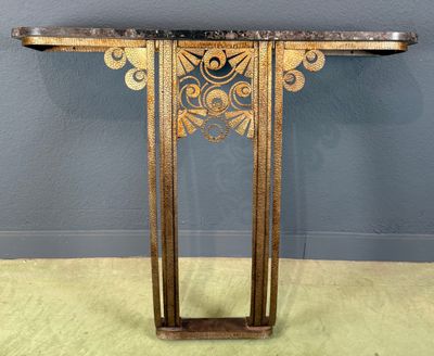une console dorée avec un plateau en marbre, posée sur un sol recouvert de moquette