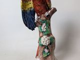 a figurine of a parrot perched on a tree branch