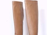 une paire de bottes marron pour femme posée sur une étagère blanche devant un mur blanc