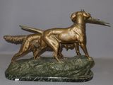 bronze statue of two dogs on a rock with a bird in its mouth