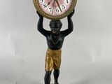 une statue représentant un homme tenant une horloge sur la tête