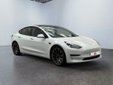 a white tesla model 3 parked in a white room