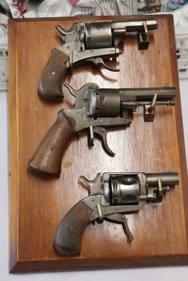 two revolvers are mounted on a wooden plaque on a table