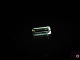 a close up of a piece of green sapphire on a black surface