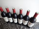 six bottles of wine are lined up on a counter top