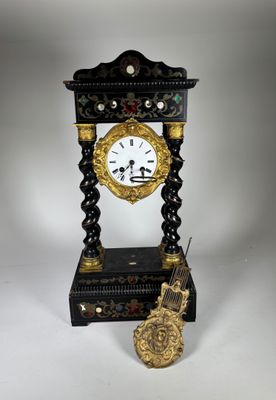 une horloge noire et dorée posée sur une table blanche