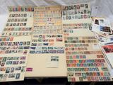 beaucoup de timbres posés sur une table, à côté d'une feuille de papier