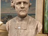 a bust of a man sitting on a shelf in front of a painting
