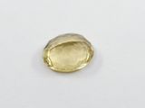 a close up of a yellow sapphire stone on a white surface