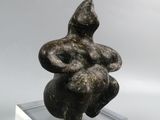 sculpture of a woman sitting on a rock on a clear base