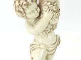 une petite statue représentant un garçon tenant une bougie, posée sur une table