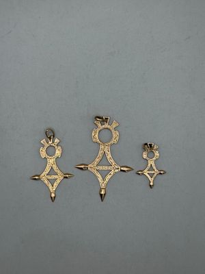 three gold pendants of different shapes and sizes on a gray surface