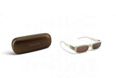 Lunettes de soleil Gucci et leur étui sur fond blanc