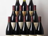 Des bouteilles de vin rouge sont posées sur une table devant un mur blanc.