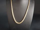 a gold necklace on a mannequin with a black background