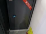 un réfrigérateur noir et un sac marron posé par terre