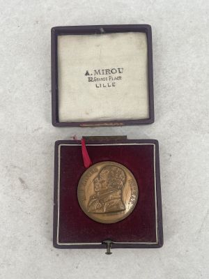 an image of a gold medal in a case with a red ribbon
