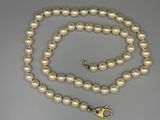 Gros plan sur un collier de perles blanches avec un fermoir en or
