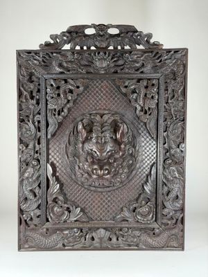 un panneau ancien en bois sculpté orné d'une tête de lion