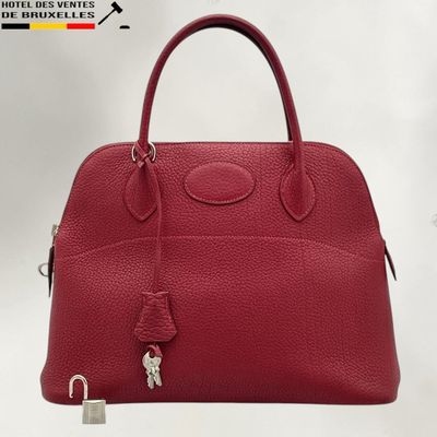un sac à main en cuir rouge muni d'un cadenas sur la poignée