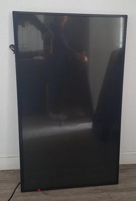 un téléviseur noir posé sur un parquet dans une pièce
