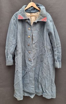 an old coat hanging on a wall with a wooden hanger