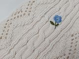 knitted white sweater with a blue flower embroidered on the side