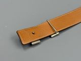 tan leather belt with silver buckle on grey surface