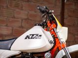 a white and orange motorcycle parked in front of a brick wall