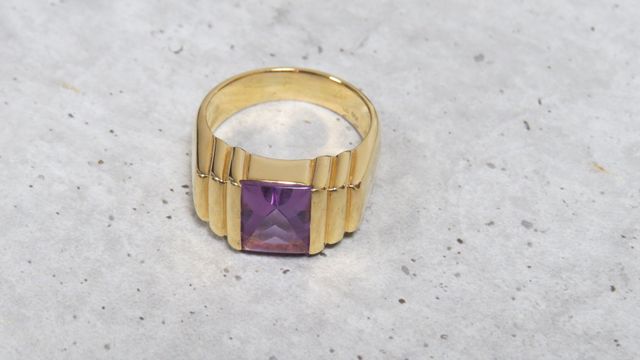 Bague en or jaune 750 millièmes, le centre orné d'une pierre viol...