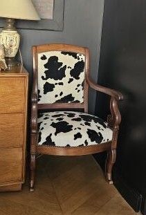 une chaise à motif vache à côté d'une commode sur laquelle est posée une lampe