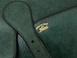 green leather handbag with a gold logo on the front