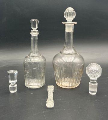 three glass bottles and a glass stopper on a table