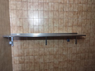 une étagère en métal dans un coin d'une salle de bains carrelée